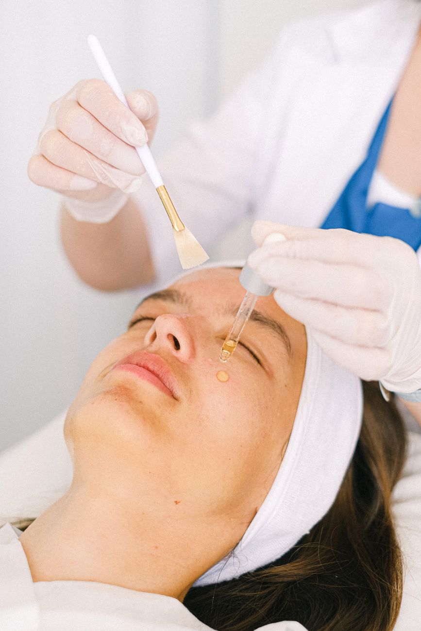 cosmetologist applying essential oil on client face